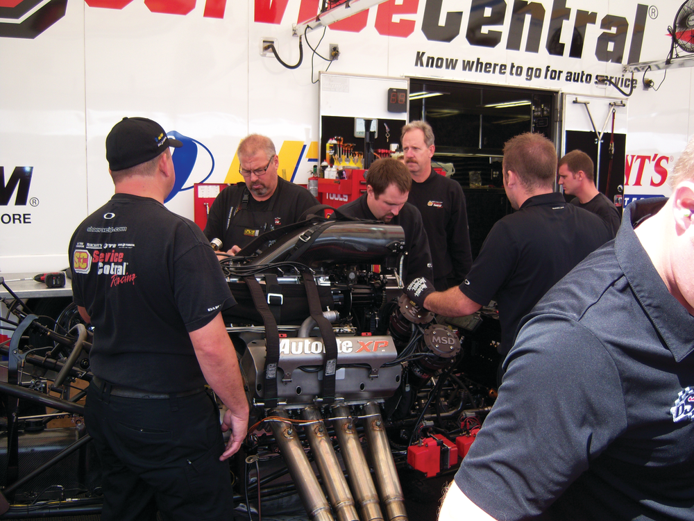 A pit crew disassembles a race car engine at Lucas Oil Raceway.