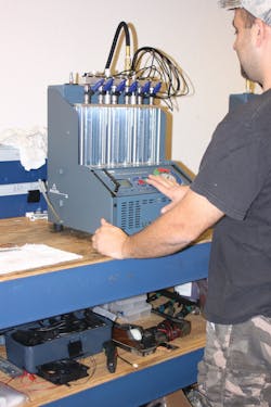 A technician tests a set of Bosch fuel injectors. A technician tests a set of Bosch fuel injectors.