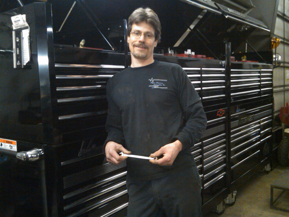 Mike Pope posing in front of his giant Mac toolbox, holding his famous 7/16' wrench.