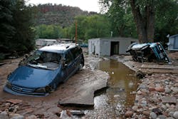 In this Sept. 13, 2013 file photo, cars lay mired in mud deposited by floods in Lyons, Colo. Little more than a year after Colorado Gov. John Hickenlooper assured the world his wildfire-ravaged state was still &ldquo;open for business,&rdquo; he may have to throw another lifeline to keep the state&rsquo;s billion-dollar tourism industry afloat. (AP Photo/Brennan Linsley, File)