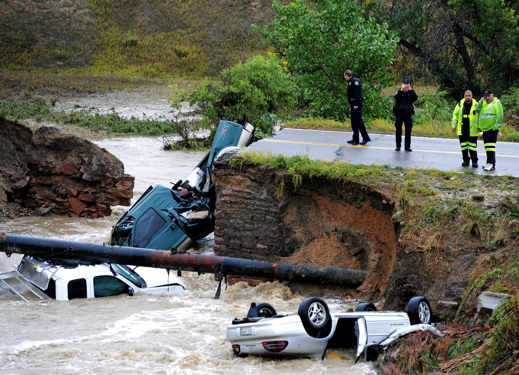 Officials investigate the scene of a road collapse at Highway 287 and Dillon at the Broomfield/Lafayette border, Colo., that sent three vehicles into the water after flash flooding on Thursday, Sept. 12, 2013. The National Weather Service has warned of an 'extremely dangerous and life-threatening situation' throughout the region. (AP Photo/Daily Camera, Cliff Grassmick)