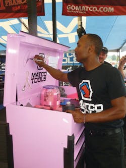 Matco Tools dragster Antron Brown signs the pink Matco Toolbox that was a raffle prize in a fund raiser for breast cancer awareness.