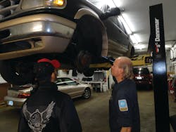 A technician examines a brake caliper using a pen light. A technician examines a brake caliper using a pen light.