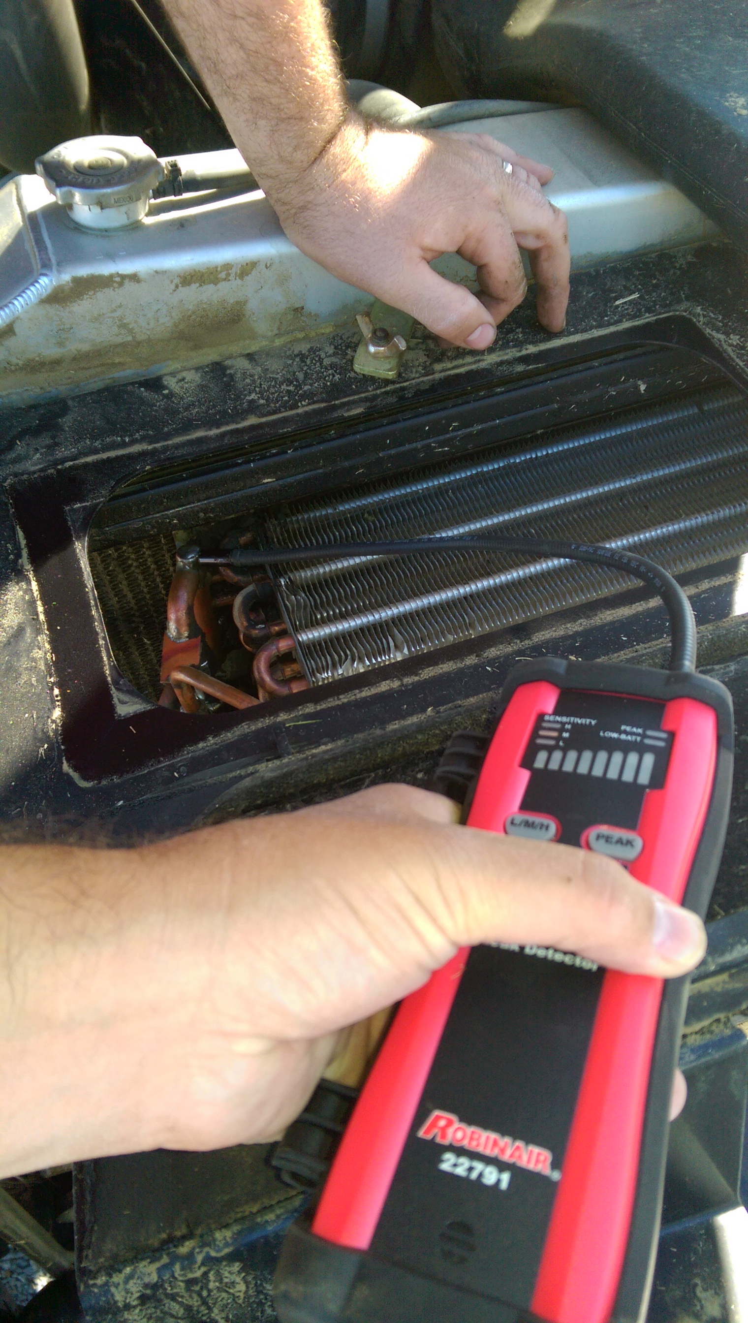 Robert Brocx uses an electronic leak detector on a condenser with a leak.