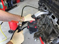 Figure 8- A typical solution for carbon removal uses media blasting. The intake manifold is removed to expose the intake ports, and media such as pulverized walnut shells are propelled against the carbon-covered surfaces using compressed shop air. The media is simultaneously recovered using a shop vac. Although messy, the process gives excellent results, and the valves/ports look brand new once the service is complete. Figure 8- A typical solution for carbon removal uses media blasting. The intake manifold is removed to expose the intake ports, and media such as pulverized walnut shells are propelled against the carbon-covered surfaces using compressed shop air. The media is simultaneously recovered using a shop vac. Although messy, the process gives excellent results, and the valves/ports look brand new once the service is complete.