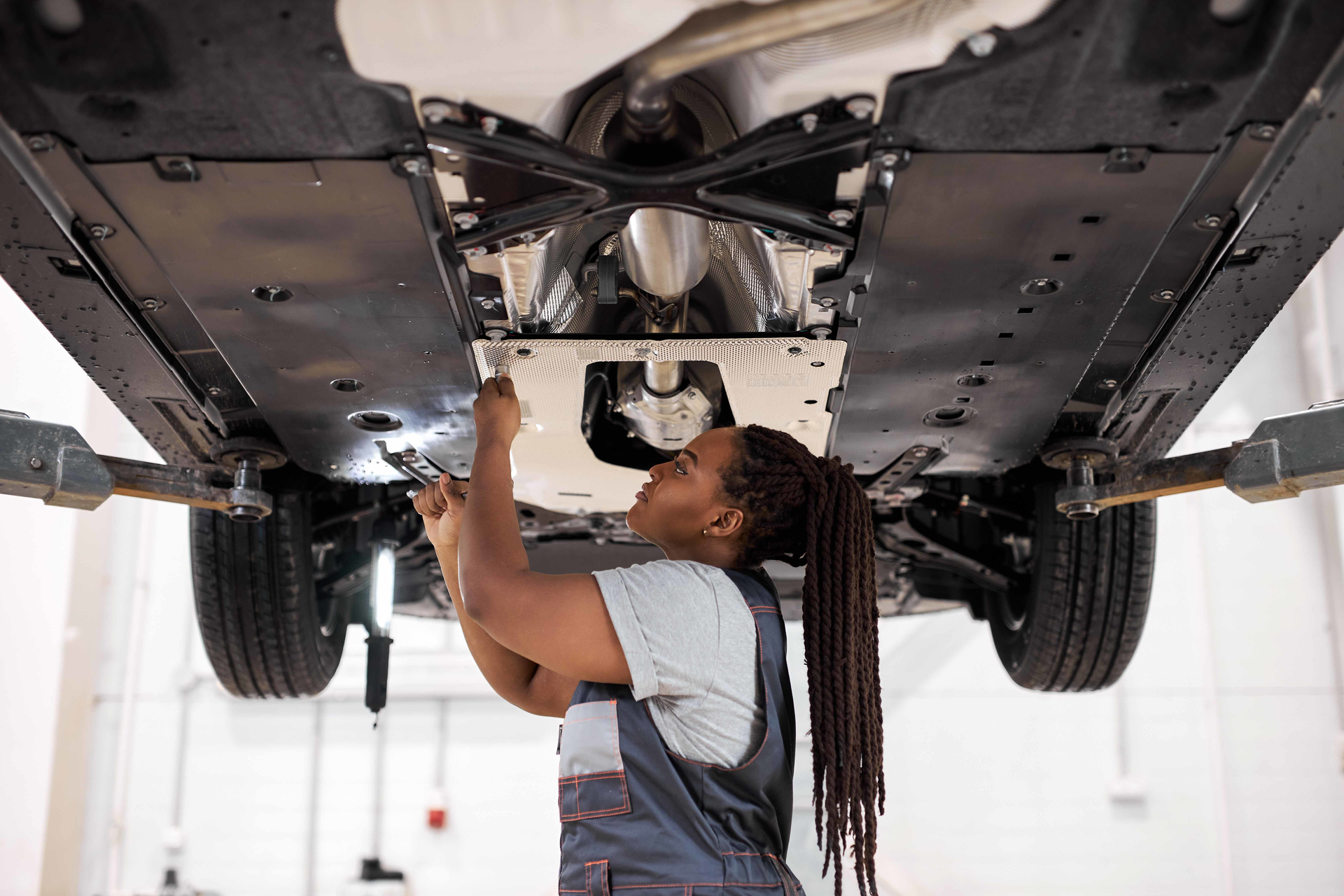 Female auto repair technician working under car