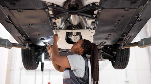 Female auto repair technician working under car