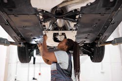 Female auto repair technician working under car