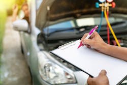 Mechanic with clipboard inspecting vehicle Mechanic with clipboard inspecting vehicle