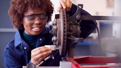 Female student working on car brakes on auto mechanic apprenticeship course at college Female student working on car brakes on auto mechanic apprenticeship course at college