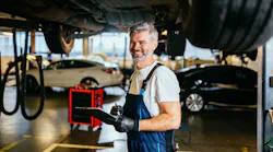 Happy automotive technician under car