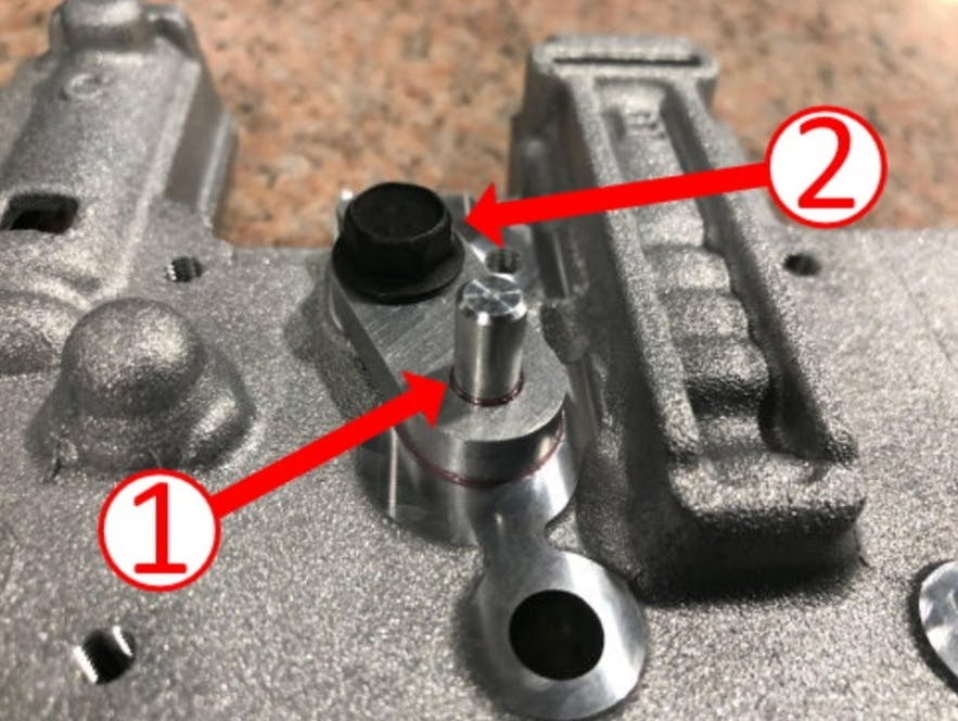 Valve body plug (1) and retaining bolt (2) locations.