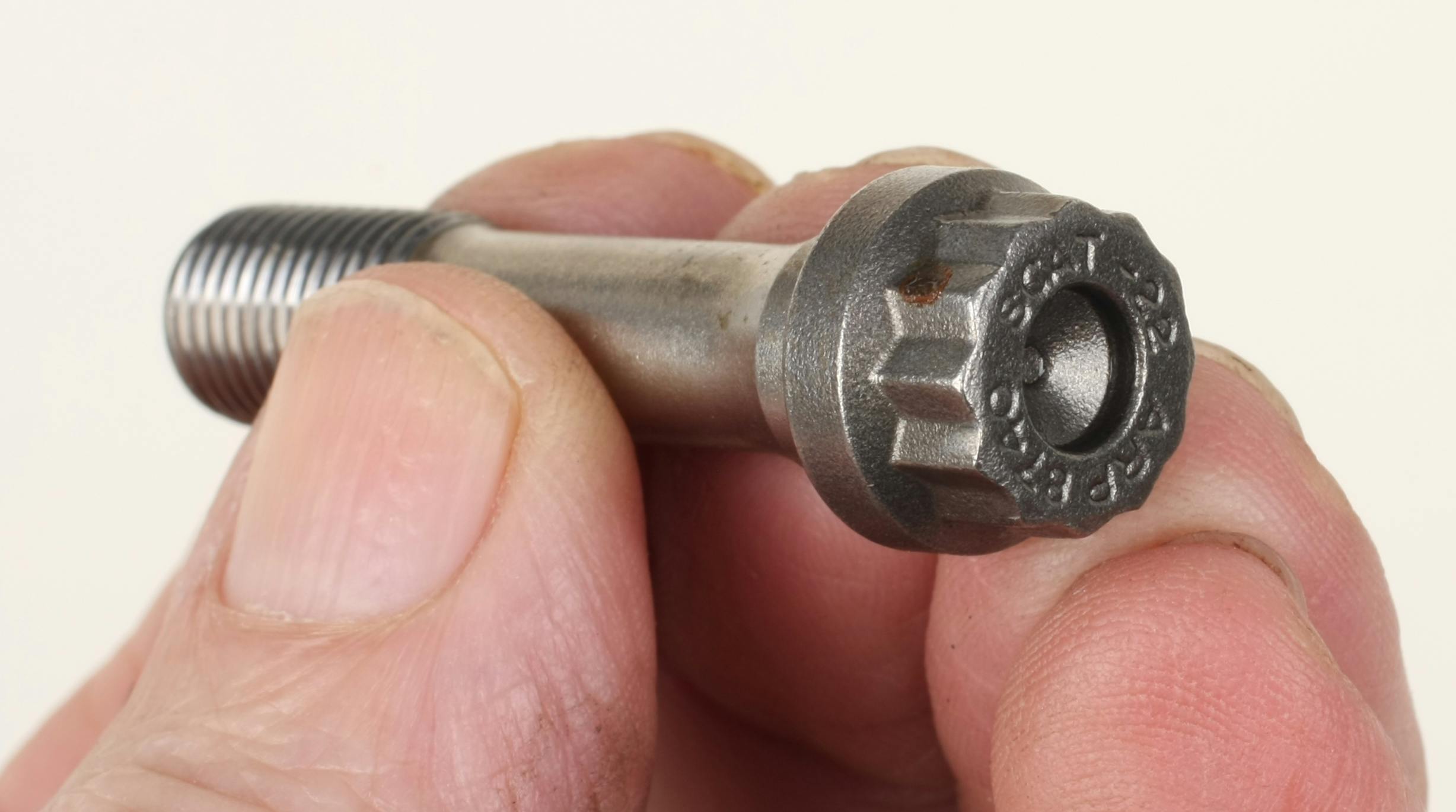 Aftermarket performance connecting rod bolts feature dimples at each end (dimple on the bolt head shown here).