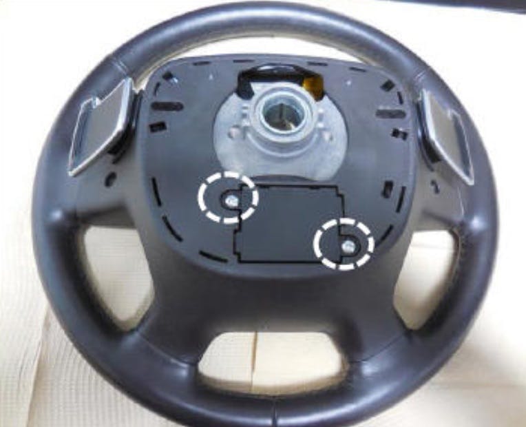 Two screws secure the haptic controller to the steering wheel assembly.