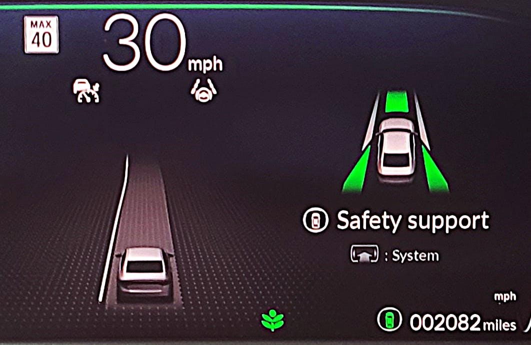 The data that the forward-facing camera has recorded and is using for its lane-keeping system is displayed in this dashboard image from a 2024 Honda Accord. The centre line, displayed as a white line, is the sole visible or dependable road marking, and the road turns to the left. It also displays the speed limit and shows that the lane keep system is currently deactivated (shown by the small white steering wheel icon) because there is insufficient data for it to function correctly.