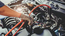 a person puts jumper cables on a car battery