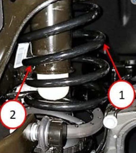 1) Badly bowed coil spring; 2) coil spring touching/too close to the jounce cup.