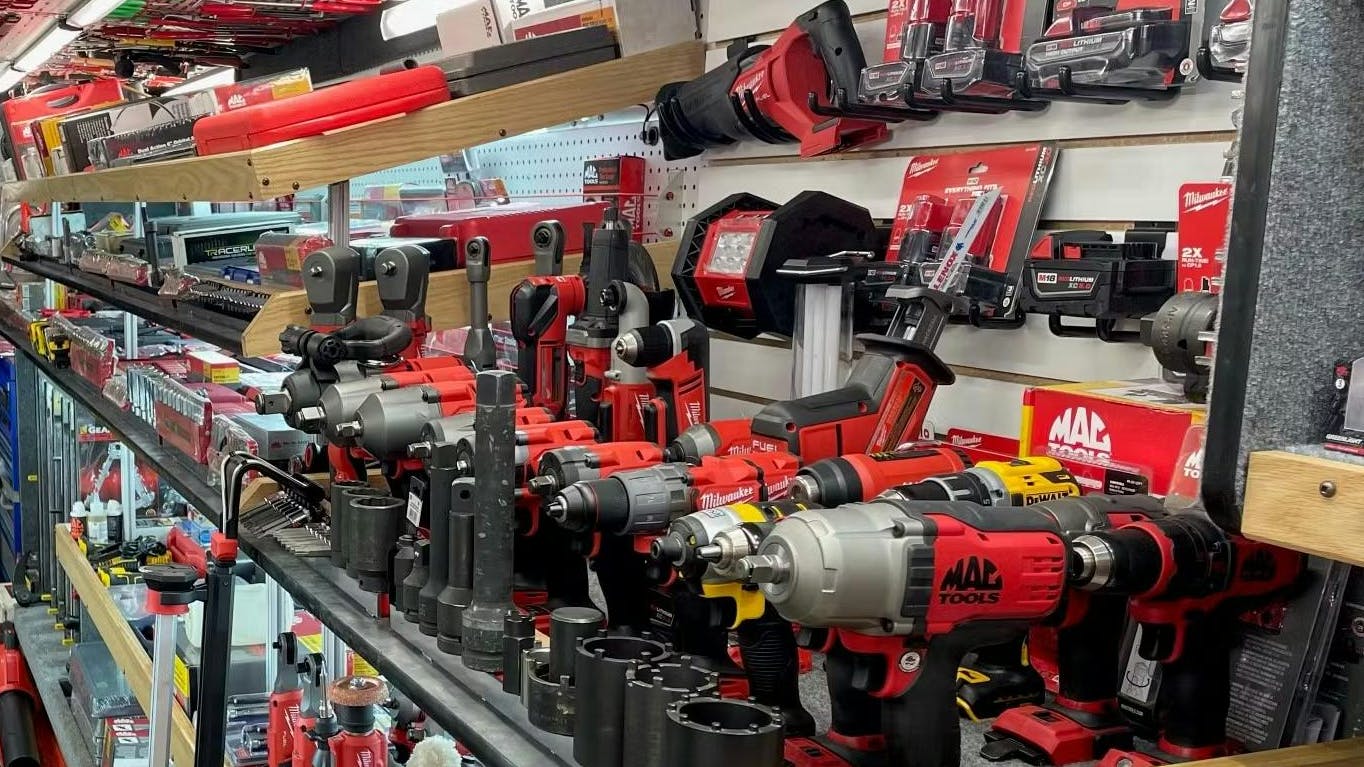 a variety of Mac Tools power tools and accessories on a shelf on a tool truck