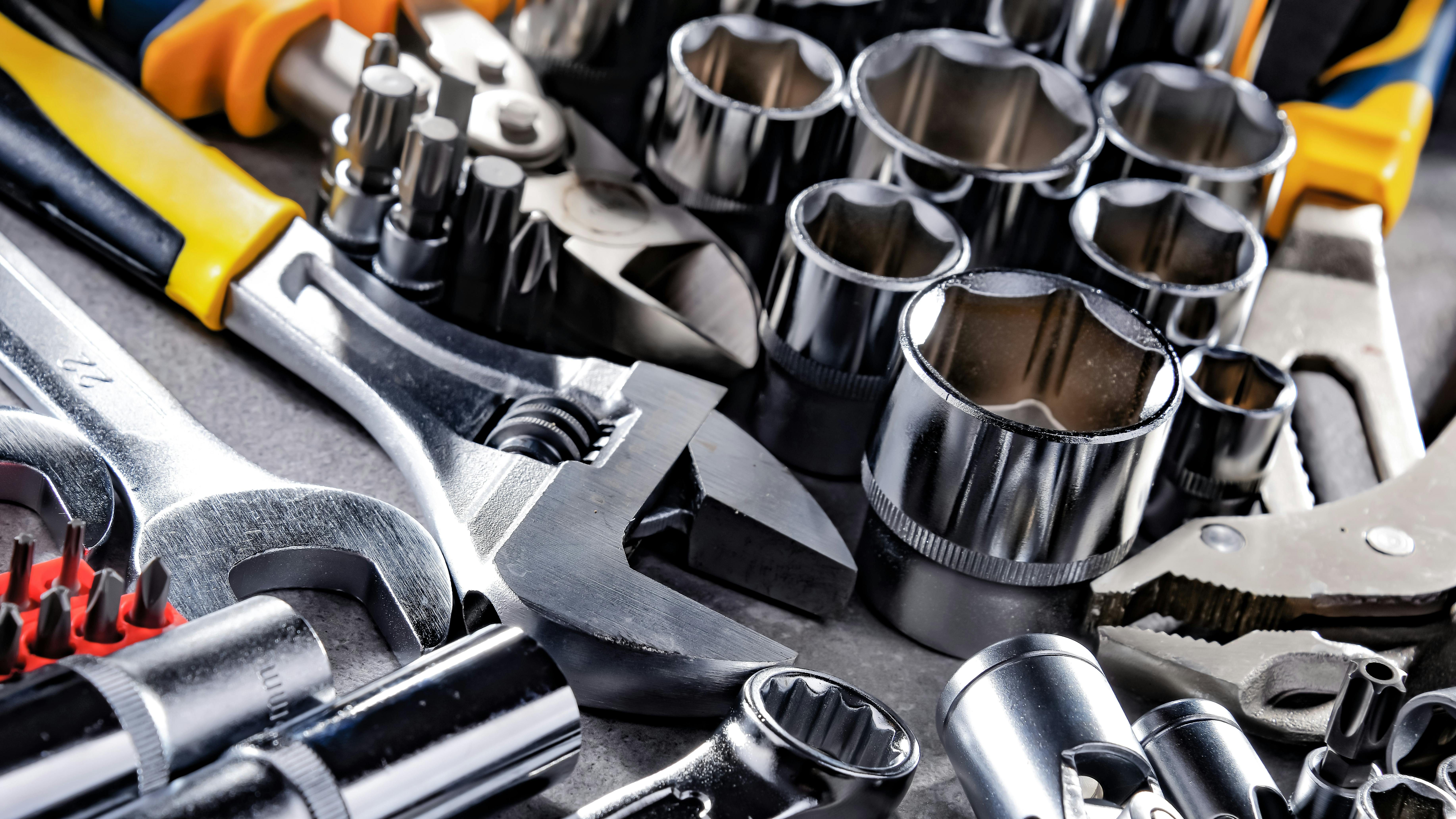 close up of a variety of wrenches, sockets, bits, and pliers on a metal table