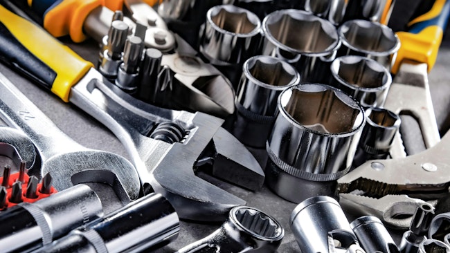 close up of a variety of wrenches, sockets, bits, and pliers on a metal table