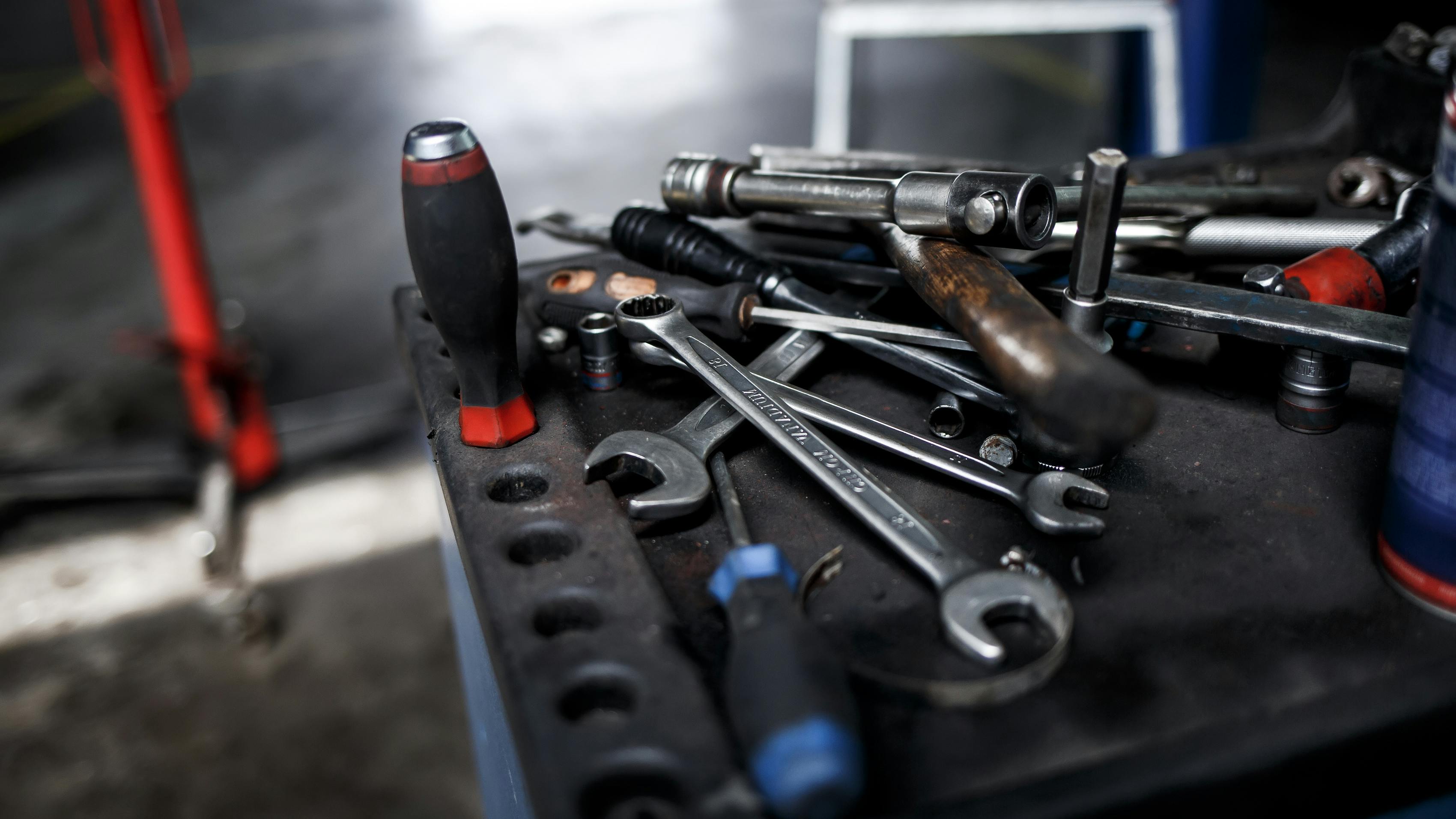a collection of automotive tools placed on a mobile worktop with a workshop out of focus