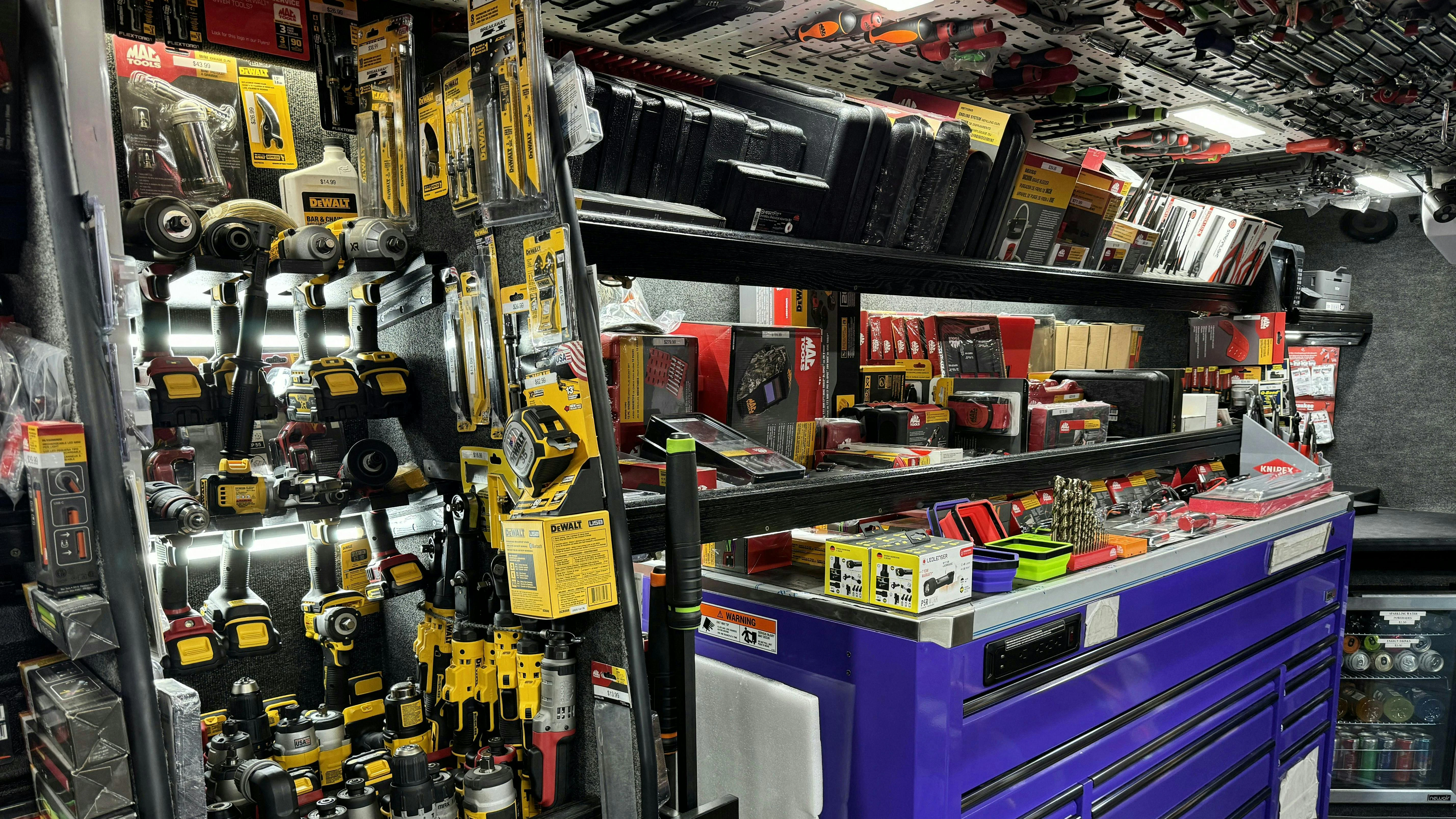 The interior of a tool truck with a large toolbox and the walls and ceiling stocked with automotive tools