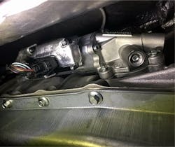 This photo shows the auxiliary electric transmission fluid pump on a 2017 Ford F-150 equipped with the 2.7L EcoBoost and Start-Stop system. This pump maintains line pressure in the transmission during engine-off events, allowing for smooth gear engagement when the engine restarts. If this pump fails, the vehicle may experience harsh shifts, delayed engagement, or Start-Stop system faults. A scan tool may reveal related DTCs or pressure drop data during Idle Stop. This photo shows the auxiliary electric transmission fluid pump on a 2017 Ford F-150 equipped with the 2.7L EcoBoost and Start-Stop system. This pump maintains line pressure in the transmission during engine-off events, allowing for smooth gear engagement when the engine restarts. If this pump fails, the vehicle may experience harsh shifts, delayed engagement, or Start-Stop system faults. A scan tool may reveal related DTCs or pressure drop data during Idle Stop.