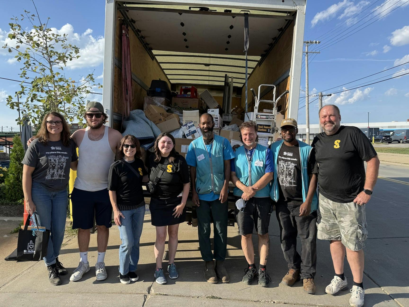 a group of eight people from Sonnhalter and Habitat for Humanity smile in front of a donations truck