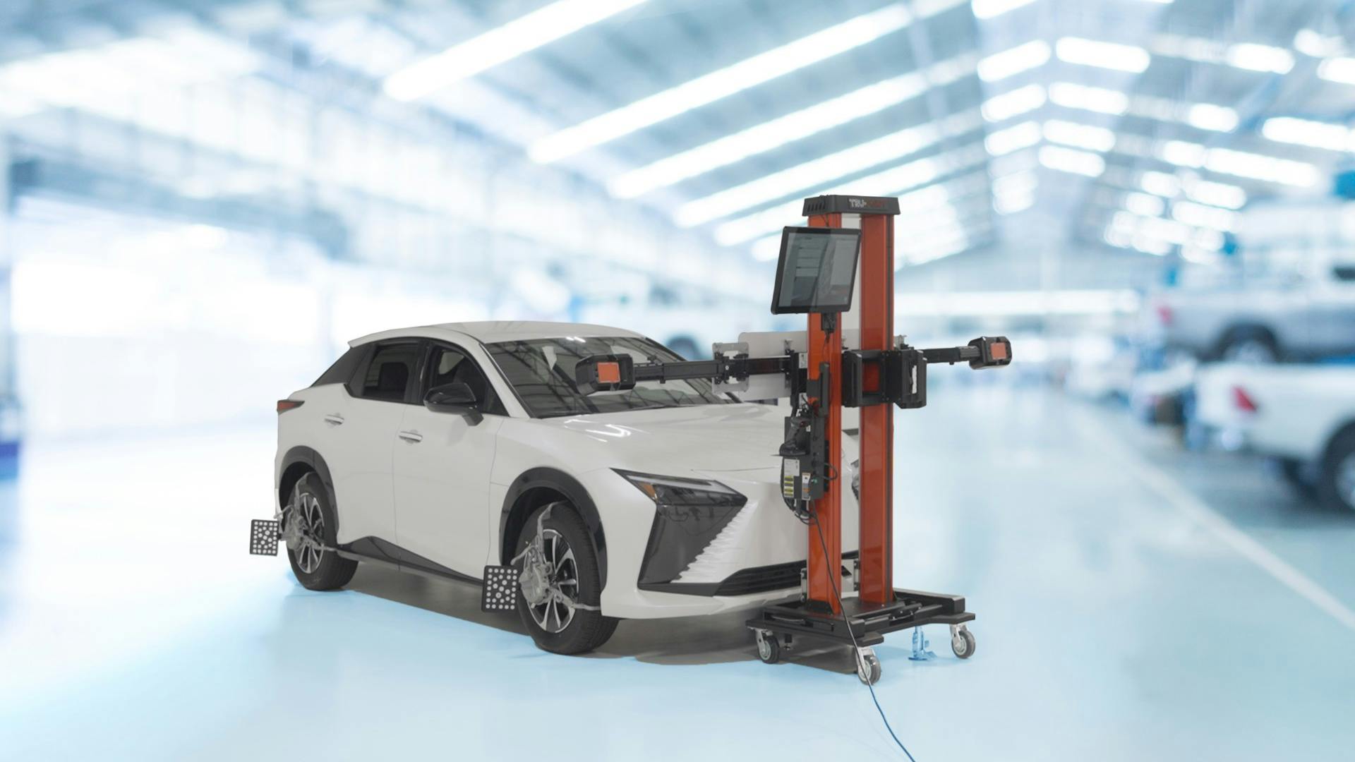 a white Lexus SUV with ADAS calibration equipment attached to its tires and in front of it