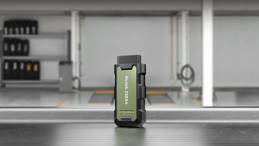 an RLink J2534 unit stands upright on a table in an automotive bay