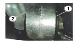 If the stabilizer link’s bushing begins to walk out (1), the housing can rub against the oil pan (2).